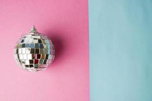 Silver mirror musical club disco ball small round glass winter shiny decorative beautiful xmas festive Christmas ball, Christmas toy plastered on glitter on a gray pink purple background photo