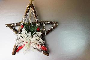 gran decorativa hermosa estrella de navidad de madera, una corona de adviento hecha a sí misma de ramas de abeto y palos en el festivo año nuevo feliz fondo gris plata alegre. decoraciones navideñas foto