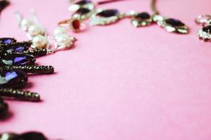 hermosas y preciosas joyas brillantes, joyas glamorosas de moda, collares, aretes, anillos, cadenas, broches con perlas y diamantes sobre un fondo rosa púrpura. endecha plana, vista superior, lugar de copia foto