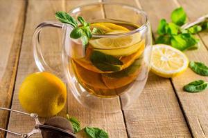 Tea with lemon and mint in transparent cup. Alternative medicine. Hot drink for relaxation. photo