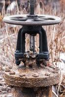 Big old rusty valve on pipe. Abandoned plumbing system. photo