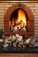 wood logs and fire in indoor brick fireplace photo