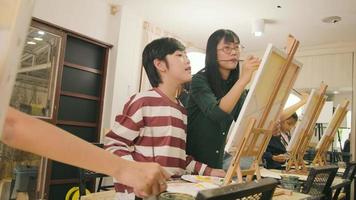 une enseignante asiatique enseigne et montre aux enfants sur la peinture acrylique couleur sur toile dans la classe d'art, apprenant de manière créative avec compétence à l'école primaire. video