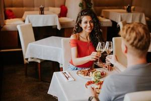 pareja joven almorzando con vino blanco en el restaurante foto