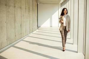 Young businesswoman walking on modern office hallway photo