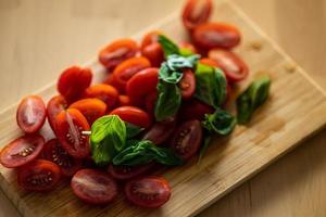 Cherry tomato and basilic on wooden background. Vegetables salad preparation photo