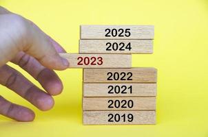Hand pulling out year 2023 text on wooden blocks. Year to year progress concept. photo