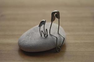 Model safety pin of parent and child sitting on a rock with customizable space for text or ideas. Family concept photo