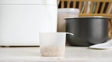 hand stirring brown rice with plastic spoon in rice cooker bowl video