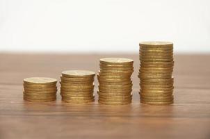 Golden coins stacked on wooden table. Wealth and business growth concept. photo