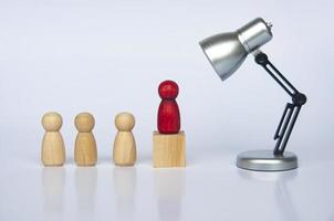 Table lamp focus on red wooden people figure on top of wooden cube leading the people figure. Leadership concept photo