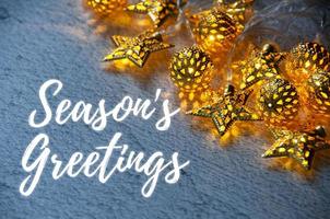 Season's greetings text with Christmas golden balls and starts light background. Christmas season concept photo