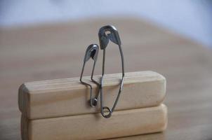 Model safety pin of parent and child sitting on wooden block with customizable space for text or ideas. Family concept photo