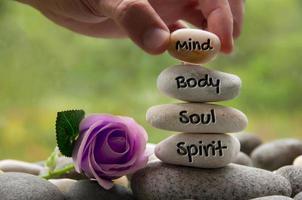 palabras de mente, cuerpo, alma y espíritu grabadas en piedras zen con flor de rosa. copie el espacio y el concepto zen foto