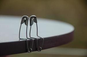 Safety pin couple sitting on table with customizable space for text and ideas. Love and romance concept photo