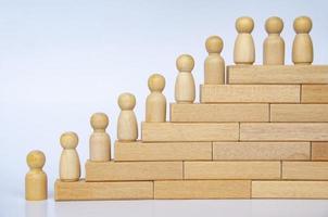 Wooden people figure on top of wooden blocks. Goal achievement, business growth and career progression photo