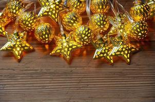 Shining Christmas golden ball and stars on wooden background with customizable space for text. Copy space photo