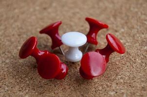 White push pin surrounded by red push pins. Harassment and discrimination concept photo