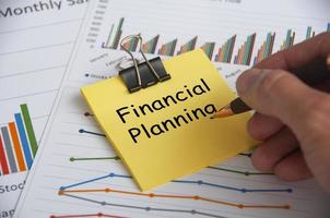 Financial planning text on yellow notepad with financial data analysis background. Financial planning concept. photo