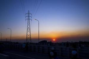 hermosa puesta de sol colorida con paisaje de pilón eléctrico de alto voltaje foto