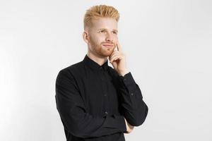 joven emprendedor genera ideas de negocios. primer plano del hombre pensante en camisa negra aislado con espacio de copia. superación personal y rostro masculino serio. chico pelirrojo con barba roja y peinado elegante foto