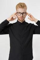 Young man in thinking process. Close up redheaded guy with red beard in black shirt, glasses focus on creating startup idea isolated on gray background. Intellect mind and brain power. Mental health. photo