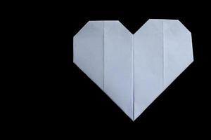 White paper folded origami love heart isolated on black background. photo