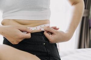 Beautiful fat woman with tape measure She uses her hand to squeeze the excess fat that is isolated on a white background. She wants to lose weight, the concept of surgery and break down fat under the photo