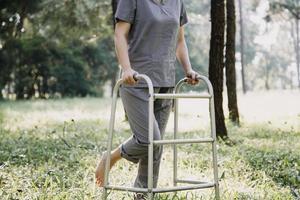 young asian physical therapist working with senior woman on walking with a walker photo