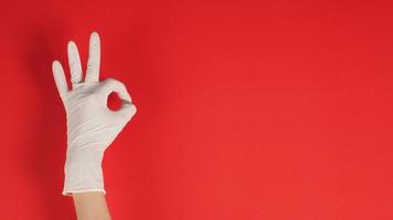 A Okay hand sign with gloves in left hand on red background. photo
