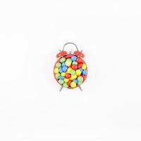 Red alarm clock with multicolor candies photo