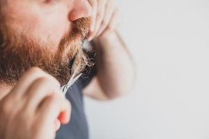 Man cutting moustache and beard himself at home photo