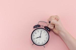 Female hand with alarm clock. Morning concept photo