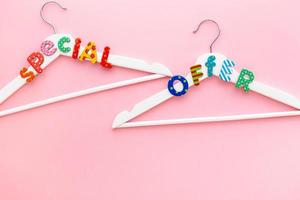 White hangers with sale text on pink background photo