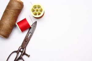 Multi-colored threads and old scissors spread out on a white floor, retro scissors, flat lay, copy space. photo