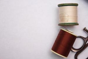 Multi-colored threads and old scissors spread out on a white floor, retro scissors, flat lay, copy space. photo