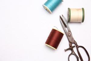 Multi-colored threads and old scissors spread out on a white floor, retro scissors, flat lay, copy space. photo