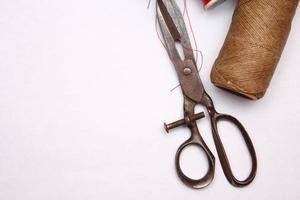 Multi-colored threads and old scissors spread out on a white floor, retro scissors, flat lay, copy space. photo