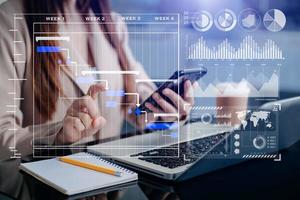 Businessman hand Project manager working and update tasks and Gantt chart scheduling virtual diagram.with smart phone, tablet and laptop in office. photo