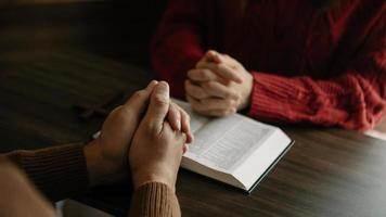 dos personas leyendo y estudiando la biblia en casa y rezando juntas. estudiando la palabra de dios con amigos. foto