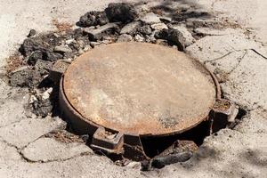 escotilla de alcantarillado de metal rota en medio de una carretera asfaltada foto