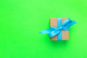 gift wrapped and decorated with blue bow on green background with copy space. Flat lay, top view photo