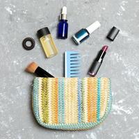 productos de maquillaje que se derraman de la bolsa de cosméticos, sobre fondo de cemento gris con espacio vacío para su diseño foto