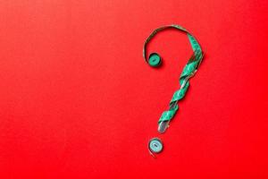 Top view of fork and measure tape in form of question mark on red background. Overeating concept and copy space photo