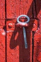 Antique iron key from a gate on a background of old red wooden gate. photo