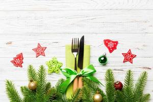Top view of christmas decorations on wooden background. Fork and knife on napkin tied up with ribbon and empty space for your design. New year pattern concept photo