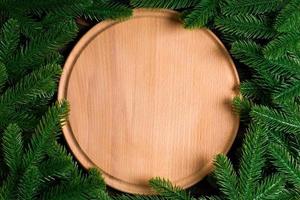 vista superior de la placa de madera decorada con ramas de abeto. concepto de cena de año nuevo con espacio vacío para tu diseño foto