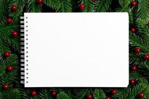 Top view of notebook decorated with a frame made of fir tree on wooden background. New Year time concept photo