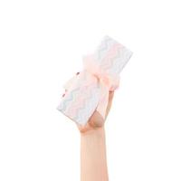 Woman hands give wrapped Christmas or other holiday handmade present in colored paper with orange ribbon. Isolated on white background, top view. thanksgiving Gift box concept photo