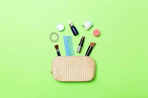 Top view od cosmetics bag with spilled out make up products on green background. Beauty concept with empty space for your design photo
